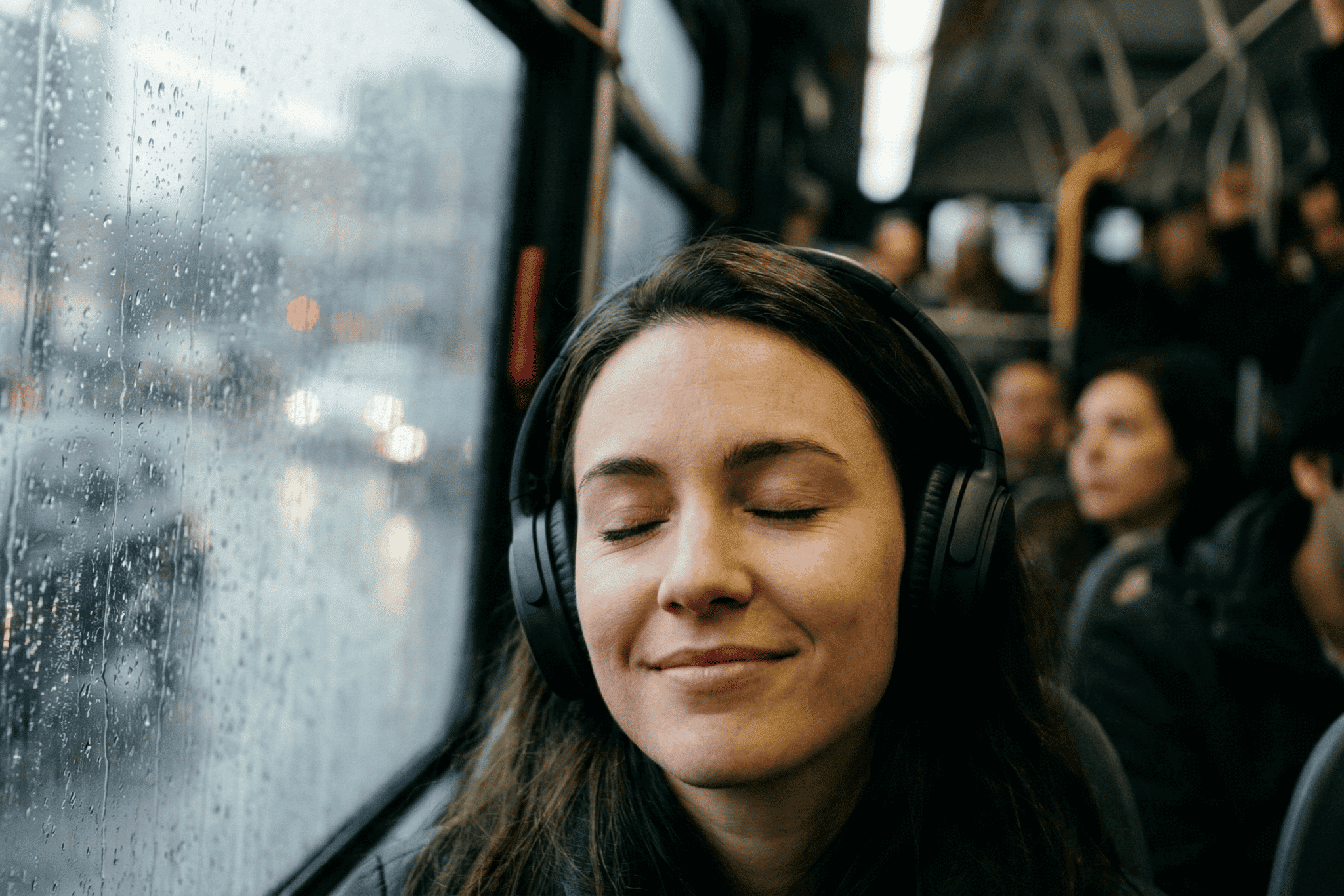 A woman on a bus listens to music on her headphones.
